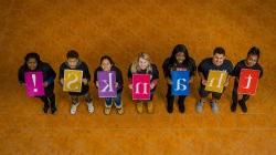 Students holding signs spelling the word Thanks.